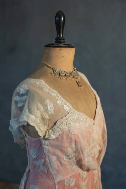 Pembe Victoria elbisesiyle klasik manken büstünde parıldayan kolye. Yan görünüm.