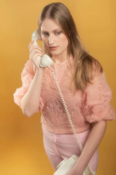 ヴィンテージ1960年代ファッション女性でピンクセーターとパンツ呼び出しでホワイト電話 — ストック写真