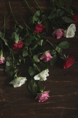 Ahşap masada bırakılmış kırmızı, pembe ve beyaz güller..