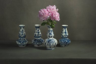 Gri bir odadaki bir masada şakayıklı dört delft mavi vazo..