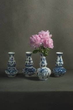 Gri bir odadaki bir masada şakayıklı dört delft mavi vazo..