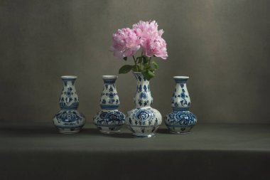 Gri bir odadaki bir masada şakayıklı dört delft mavi vazo..