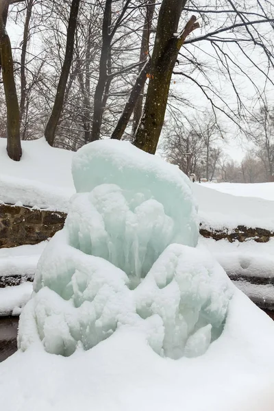 Invierno hermosa cascada congelada o fuente con carámbanos en cascada de goteo de agua en el parque de la ciudad — Foto de Stock