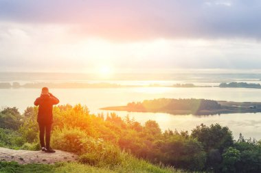 Uzun yürüyüşe çıkan kimse fotoğraf dağ tepe üzerinde akıllı telefonla güneş doğarken alıyor.