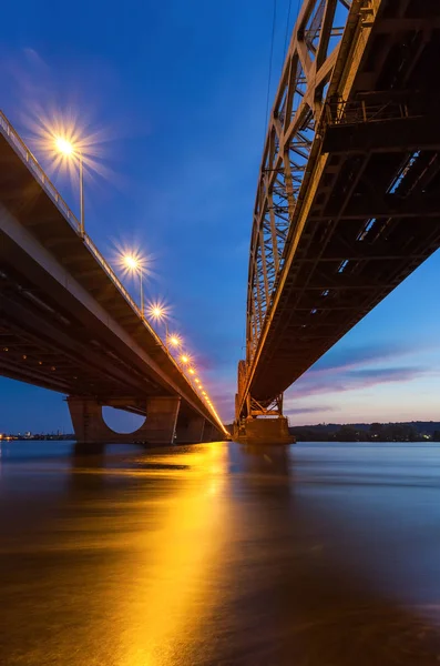 Automóvel e ponte ferroviária em Kiev, a capital da Ucrânia. Ponte ao pôr do sol através do rio Dnieper . — Fotografia de Stock