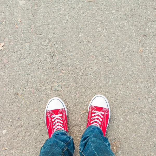 Νεαρός πόδια σε κόκκινο πάνινα παπούτσια σε καλντερίμι — Φωτογραφία Αρχείου