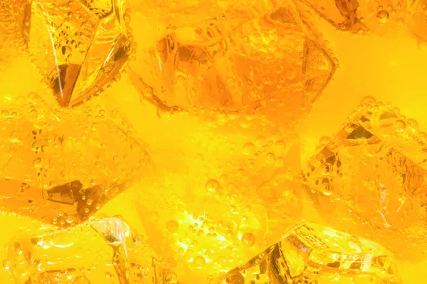 Närbild av isbitar i dryck eller orange juice — Stockfoto