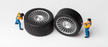 Atölye lastiği provası konsepti. Minyatür tamirciler oyuncak araba tekerleğini tamir ediyor. Kapatın..