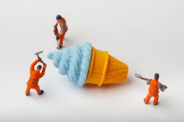 Minyatür insanlar dondurma, yemek pişirme ve dekorasyon konsepti taşıyorlar. Herhangi bir soruna toplu çözüm kavramı. Yakın çekim görünümü.