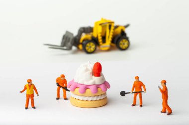 Minyatür insanlar pastayı çilek, yemek pişirme ve dekorasyon konseptiyle taşır. Herhangi bir soruna toplu çözüm kavramı.