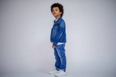 Esmer çocuk kot ve beyaz bir süveterin içinde farklı pozlar farklı duygular farklı arka plan üzerinde gösterir.