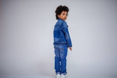 Esmer çocuk kot ve beyaz bir süveterin içinde farklı pozlar farklı duygular farklı arka plan üzerinde gösterir.