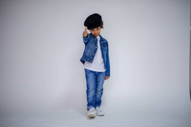 Esmer çocuk kot ve beyaz bir süveterin içinde farklı pozlar farklı duygular farklı arka plan üzerinde gösterir.