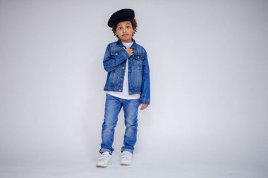 Esmer çocuk kot ve beyaz bir süveterin içinde farklı pozlar farklı duygular farklı arka plan üzerinde gösterir.