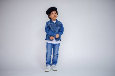 Esmer çocuk kot ve beyaz bir süveterin içinde farklı pozlar farklı duygular farklı arka plan üzerinde gösterir.