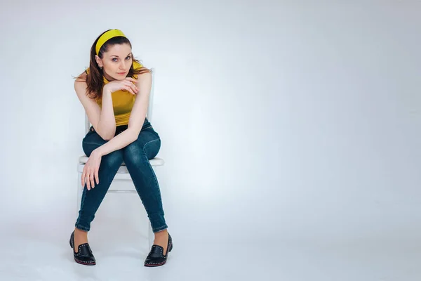 Menina Bonita Uma Cadeira Uma Camiseta Amarela Fundo Branco — Fotografia de Stock