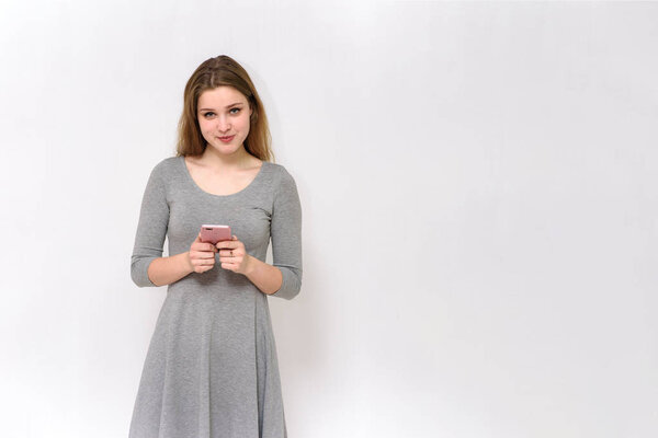 beautiful girl is typing a message on the smartphone on a white background 