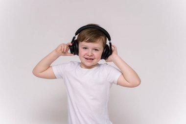 6 yaşındaki yakışıklı beyaz bir arka planda farklı pozlar kulaklıktan müzik dinleme