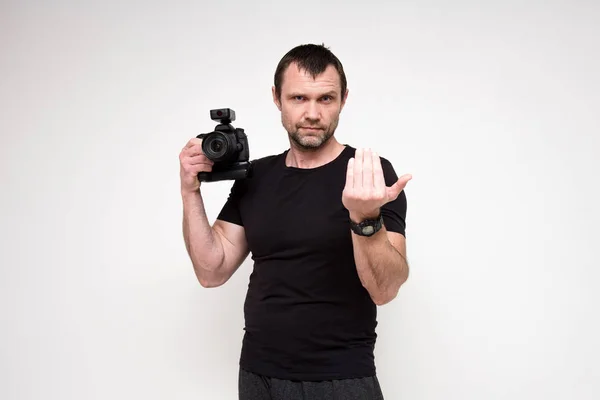 Portret van een mooie fotograaf op een witte achtergrond met een camera in zijn hand — Stockfoto