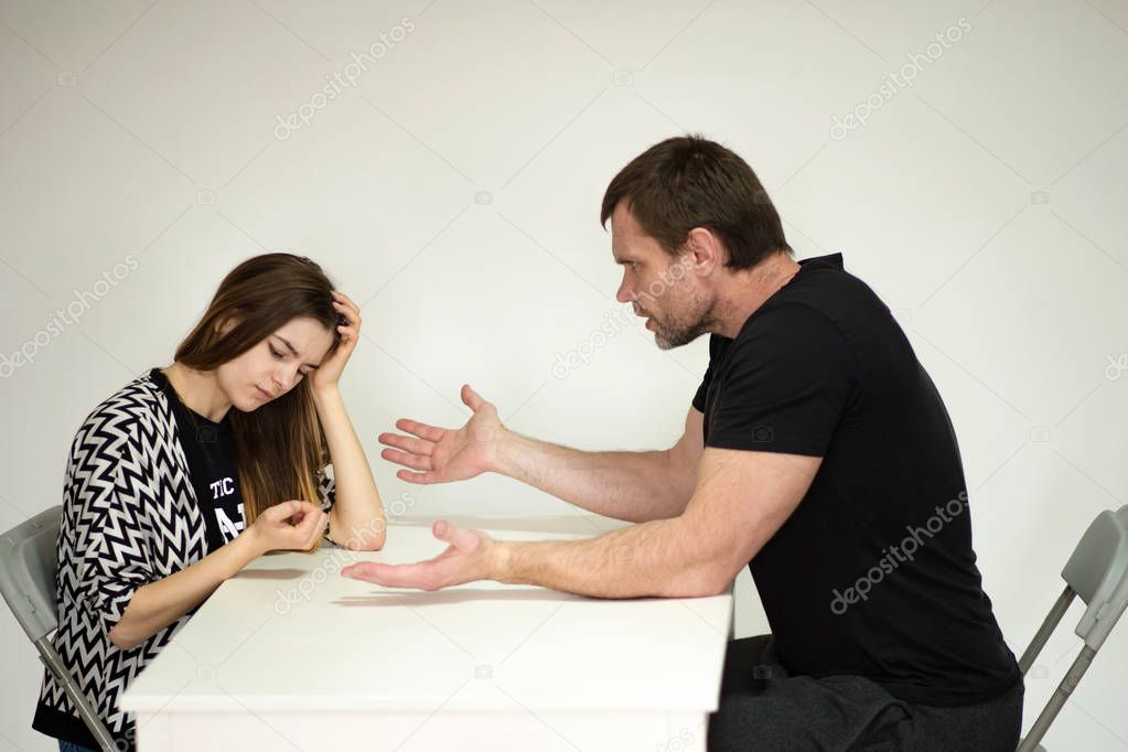 family quarrel: father and daughter teenager sitting at the table