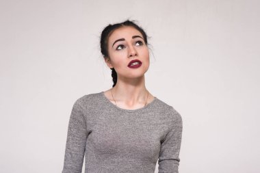 Duygularını gösterilen gri arka plan üzerinde güzel bir esmer kız portresi