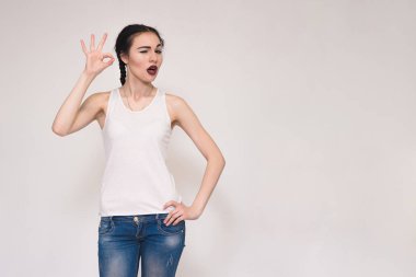 Gri arka plan üzerinde gösterilen ok mutlu güzel esmer kız portresi.