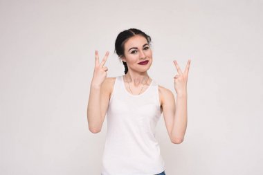 T-shirt parmakları gösterilen gri bir arka plan üzerine bir güzel esmer kız portresi