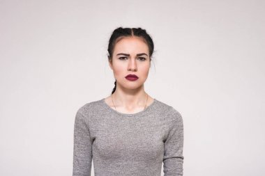 Hoşnutsuzluğunu gösterilen beyaz zemin üzerine güzel bir esmer kız portresi