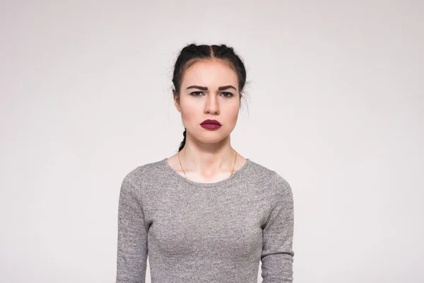 Portrait of a beautiful brunette girl on a white background showing displeasure