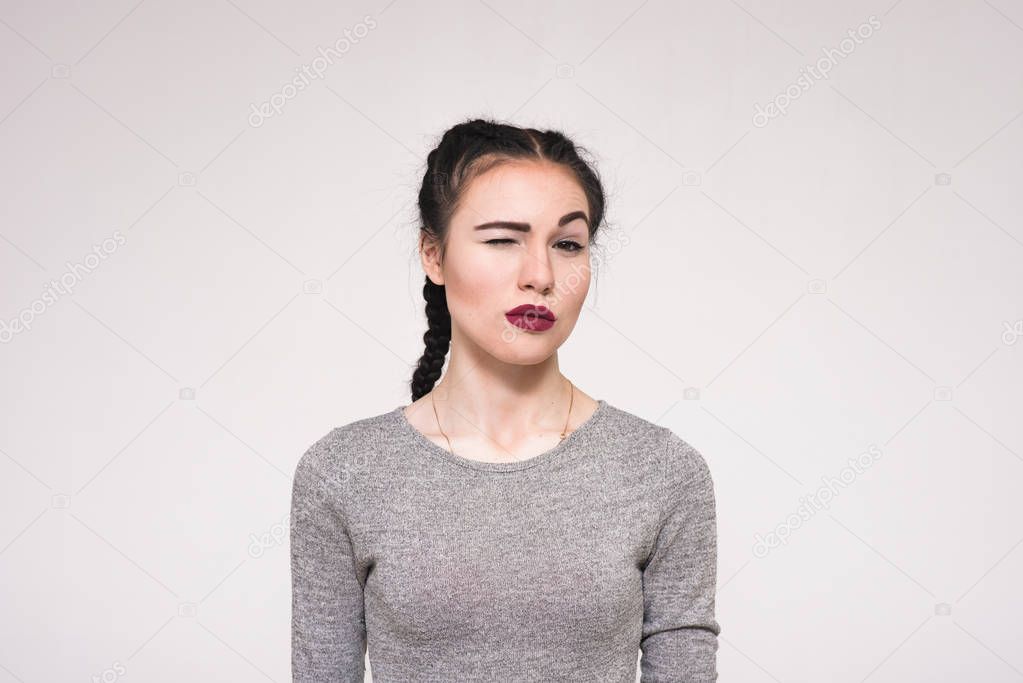 Portrait of a beautiful brunette girl on a white background showing displeasure