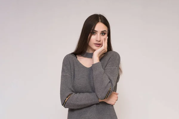 Beautiful brunette girl on a gray background shows surprise — Stock Photo, Image