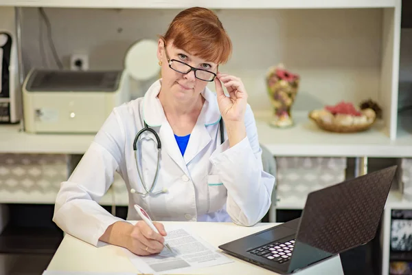 Doctor sentado en la oficina con el ordenador portátil y trabajando — Foto de Stock