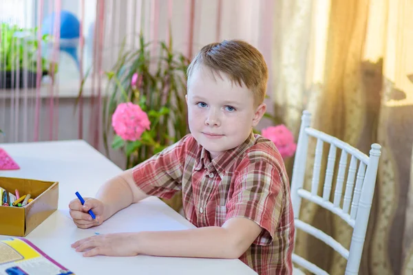 Ένα αγόρι 6 ετών, ενώ κάθεται σε ένα τραπέζι — Φωτογραφία Αρχείου
