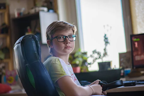 14 年間の 10 代の少年はコンピューター ゲームで座っています。. — ストック写真