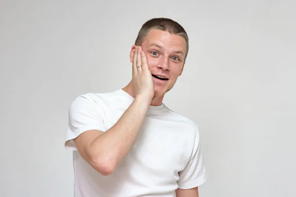 Oh, my God, I do not believe my eyes. Portrait of a surprised young man on a white background. He stands in front of the camera smiling and looks surprised