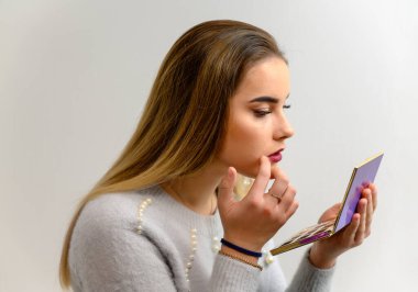 Kendine makyaj yapan güzel bir kızın stüdyo fotoğrafı. Güzel makyajlar ve saç şekilleri yaratıyor, cildini tazeliyor..