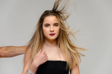 Uzun, dalgalı saçları ve gri bir arka planda farklı pozlarda mükemmel makyajı olan güzel bir kızın büyük stüdyo fotoğrafı. Gülümsüyor..