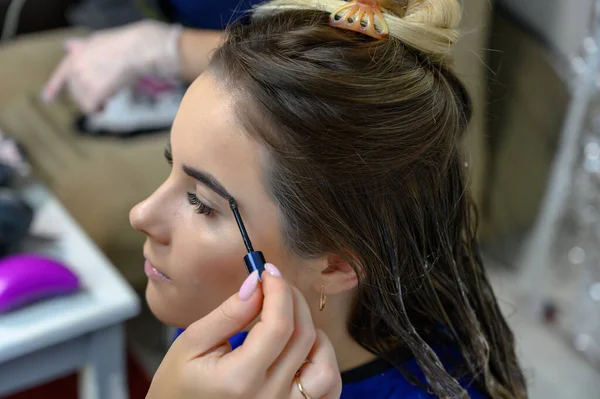 Studio photo of the work of a makeup artist by a hairdresser beautician. Creating beautiful makeup and hairstyles, rejuvenating the skin of the face. The professional is working with special tools.