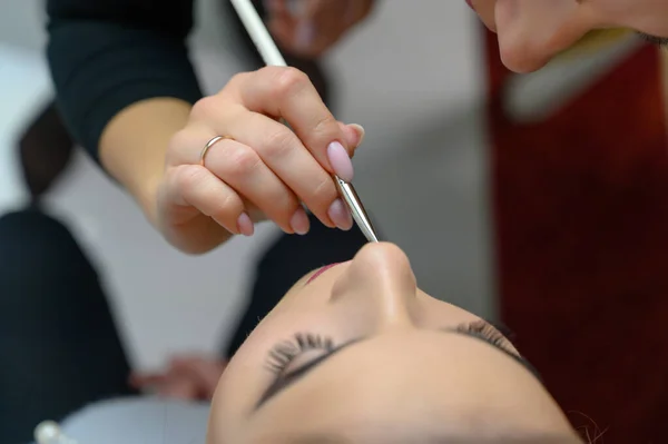 Foto de estúdio do trabalho de um maquiador por um esteticista cabeleireiro. Criando maquiagem bonita e penteados, rejuvenescendo a pele do rosto. O profissional está trabalhando com ferramentas especiais . — Fotografia de Stock