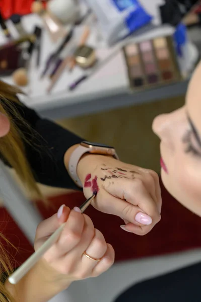 Studio photo of the work of a makeup artist by a hairdresser beautician. Creating beautiful makeup and hairstyles, rejuvenating the skin of the face. The professional is working with special tools.