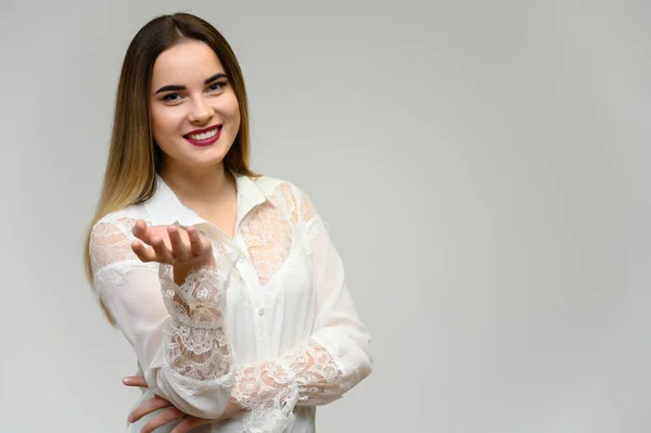 Retrato de estúdio de uma menina bonita com cabelo longo e bonito e excelente maquiagem em um fundo cinza. Ela está a falar com a câmara. . — Fotografia de Stock