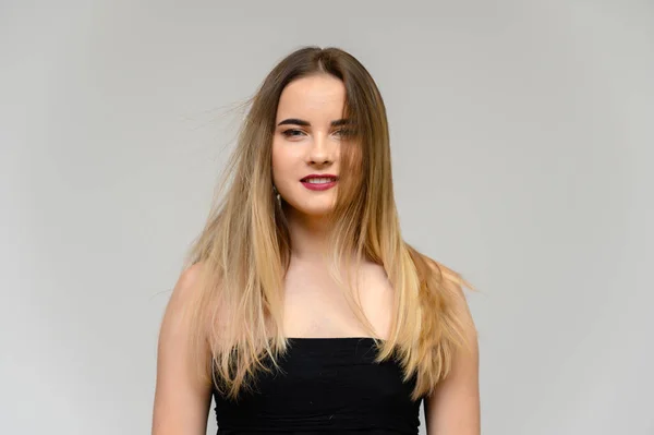 Studio großes Fotoporträt eines schönen Mädchens mit langen, schön fließenden Haaren und ausgezeichnetem Make-up auf grauem Hintergrund in verschiedenen Posen. sie lächelt. — Stockfoto