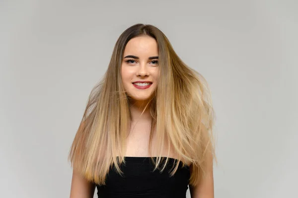 Estúdio grande foto retrato de uma menina bonita com cabelo longo e bonito fluindo e excelente maquiagem em um fundo cinza em diferentes poses. Ela sorri. . — Fotografia de Stock