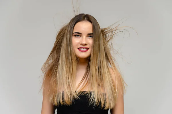 Studio grote foto portret van een mooi meisje met lang mooi stromend haar en uitstekende make-up op een grijze achtergrond in verschillende poses. Ze lacht.. — Stockfoto