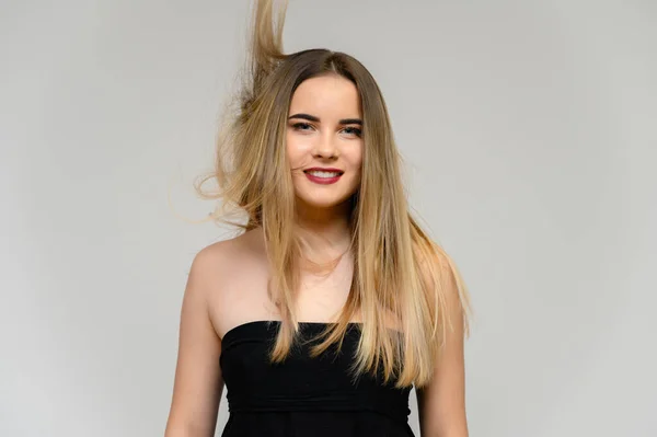 Estúdio grande foto retrato de uma menina bonita com cabelo longo e bonito fluindo e excelente maquiagem em um fundo cinza em diferentes poses. Ela sorri. . — Fotografia de Stock