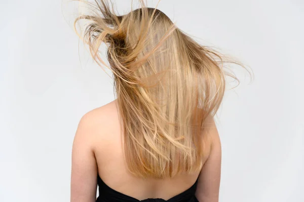 Estúdio grande foto retrato de uma menina bonita com cabelos longos e bonitos fluttering em um fundo branco. Visão traseira . — Fotografia de Stock