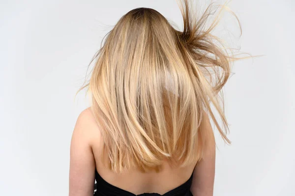 Estudio foto grande retrato de una hermosa chica con pelo largo y hermoso revoloteando sobre un fondo blanco. Vista trasera . —  Fotos de Stock