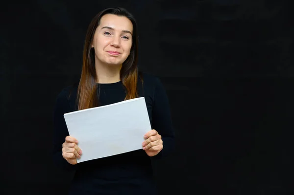 Ritratto di donna adulta senza trucco con pelle pulita, con lunghi capelli castani sul viso su sfondo nero. Sta davanti alla telecamera con una maglietta nera, mostra le sue emozioni alle mani . — Foto Stock