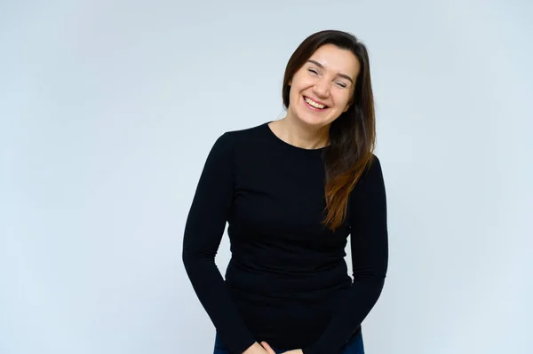 Retrato de una mujer adulta sin maquillaje con la piel limpia, con el pelo largo y castaño sobre su cara sobre un fondo blanco. Se para frente a la cámara con una camiseta negra, muestra sus manos emociones . — Foto de Stock