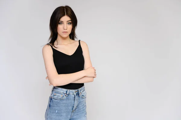 Retrato de uma jovem estudante bonita com cabelo preto longo, em um fundo branco. Ele fica bem na frente da câmera, mostrando suas mãos em poses diferentes com emoções diferentes. . — Fotografia de Stock